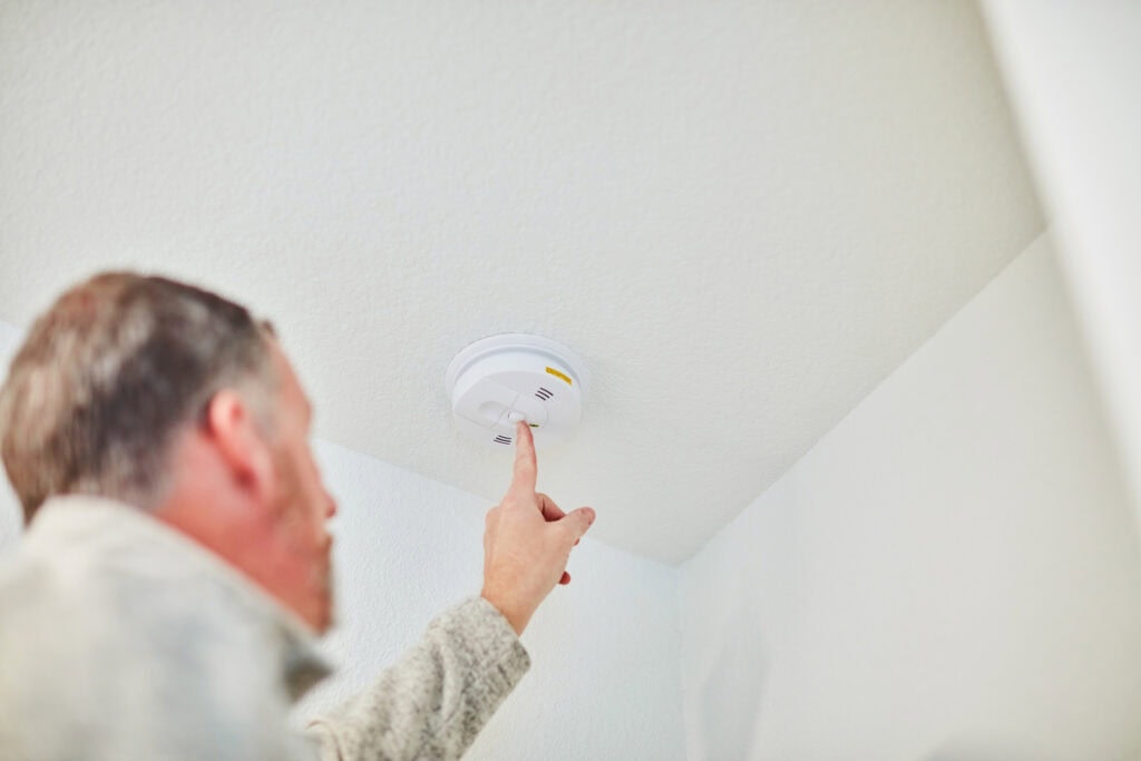 man testing smoke alarm in home
